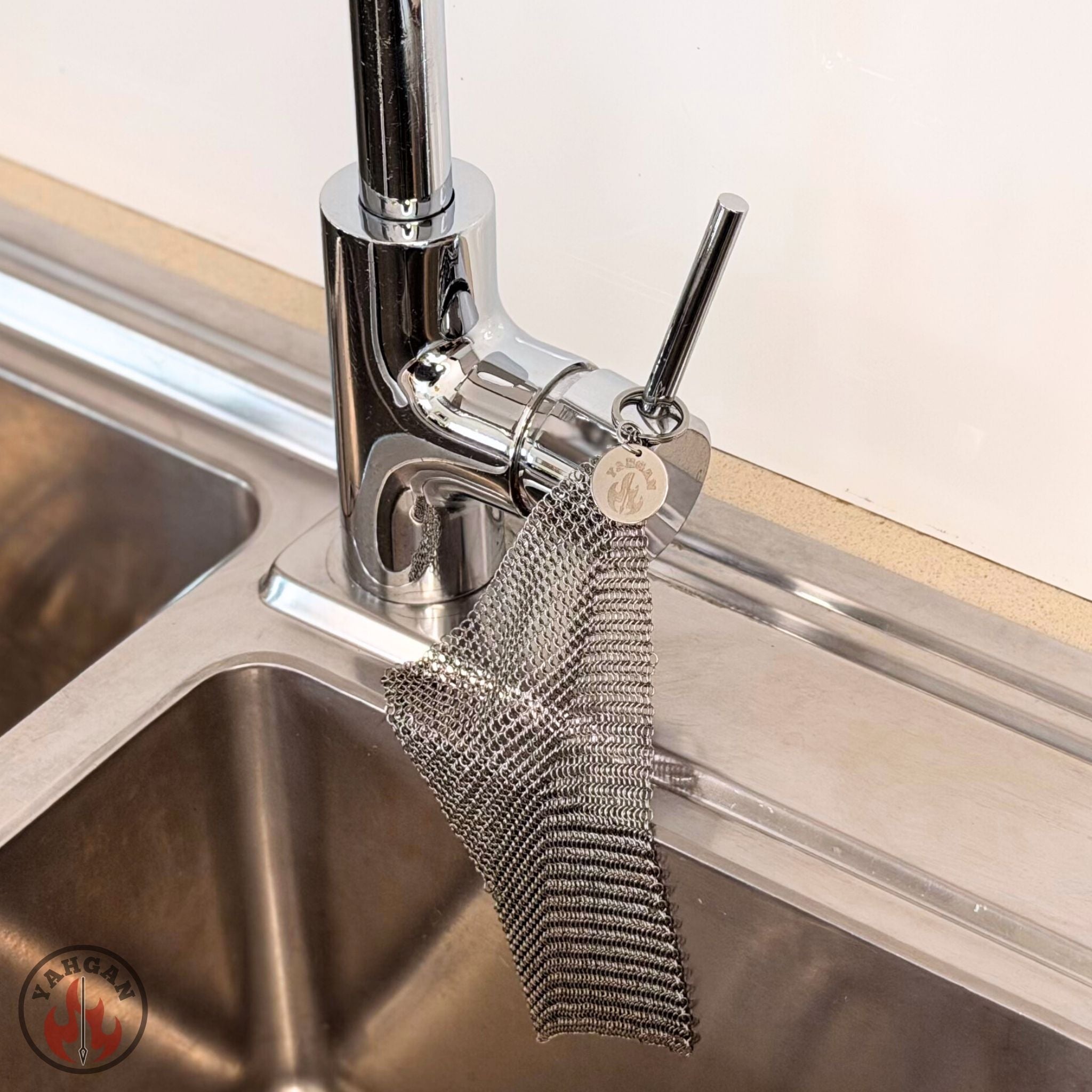 Yahgan chainmail scrubber hanging from kitchen tap to air dry — hanging ring storage for carbon steel pan care kit