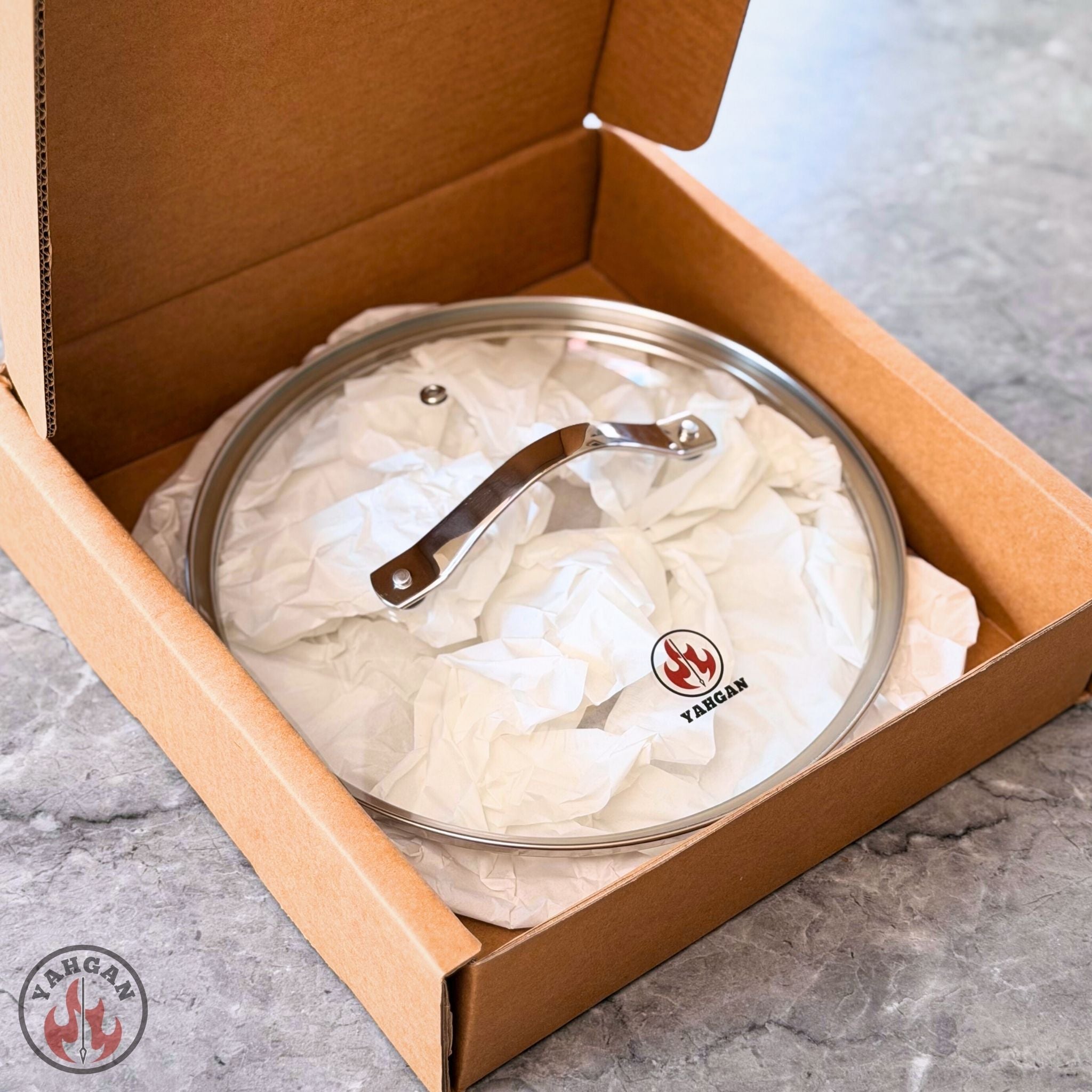 Yahgan tempered glass lid 26cm in open gift box — stainless steel handle and Yahgan logo, gift-ready packaging
