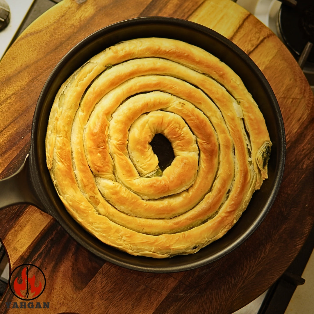 Spanakopita cooking in Yahgan Classic Series 26cm carbon steel pan — naturally non-stick surface built through seasoning